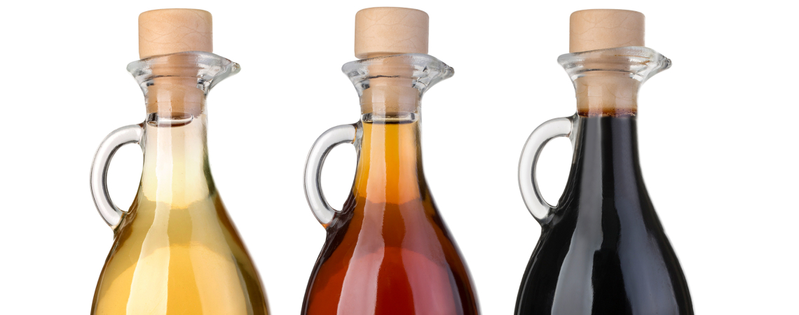 Drei Glasflaschen mit hellem, bernsteinfarbenem und dunklem Inhalt, jede mit Korkverschluss.