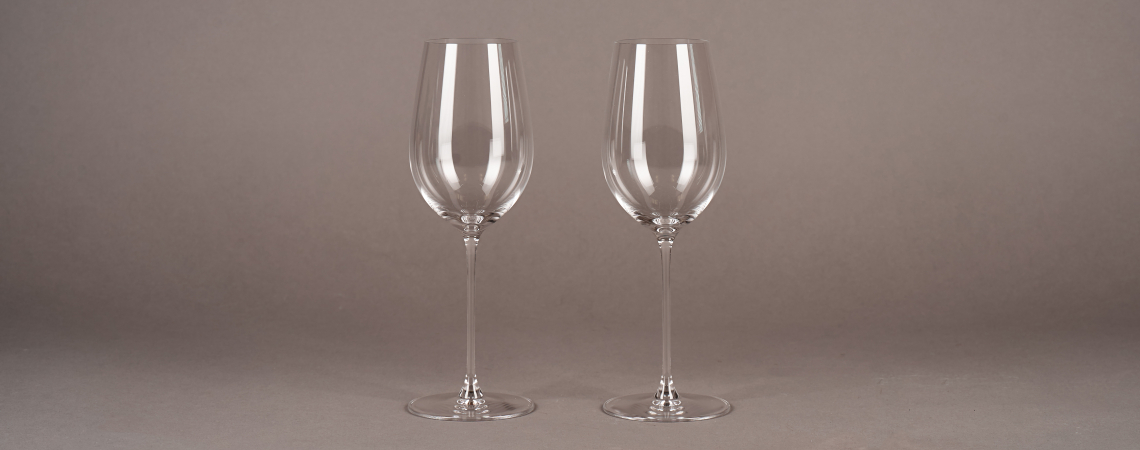 Zwei elegante, langstielige Weingläser auf grauem Hintergrund.