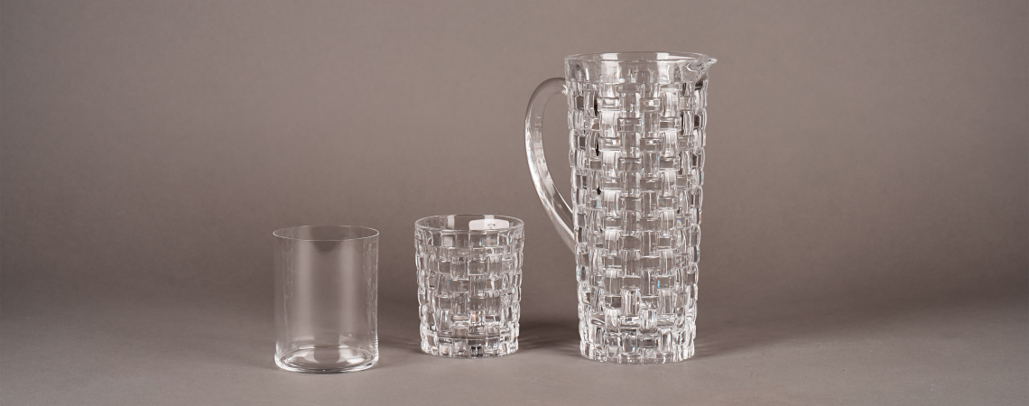 Klarglas-Krug und zwei Gläser, eines mit Rautenmuster, auf grauem Hintergrund.