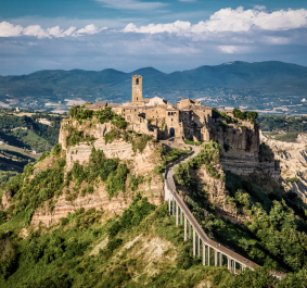 Mittelalterliches Dorf auf einem Hügel, umgeben von üppiger Landschaft und Bergkulisse.