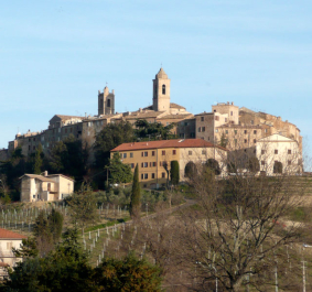 Historische Hügelstadt mit alten Gebäuden und Türmen unter blauem Himmel.