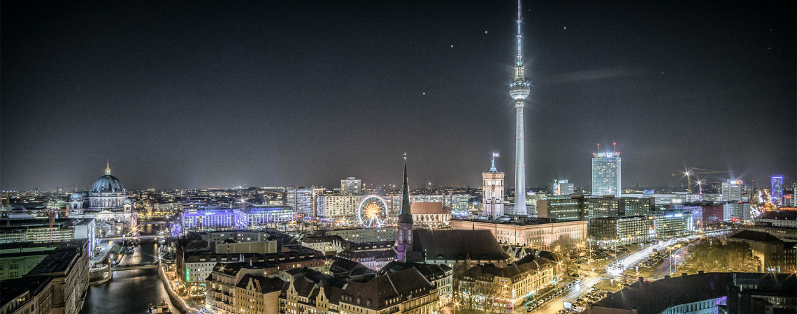Nächtliche Berliner Skyline mit Fernsehturm und beleuchteten Gebäuden.