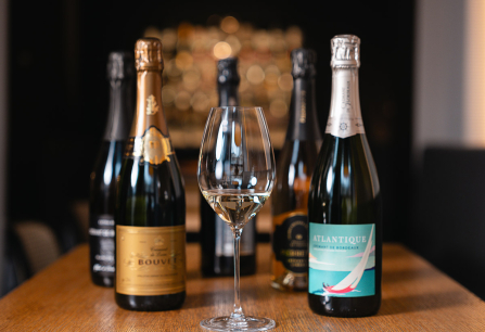 Weingläser und Sektflaschen auf einem Holztisch, Hintergrund unscharf.