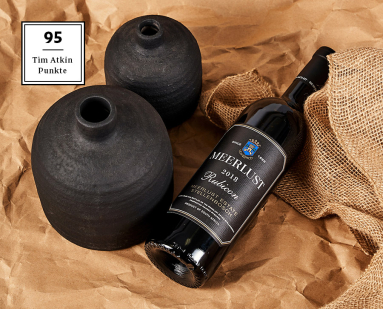 Schwarze Weinflasche und zwei matte Vasen auf braunem Stoffhintergrund.