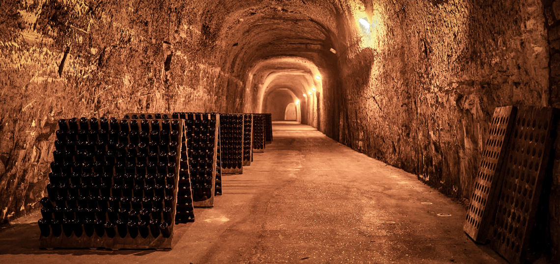 Historischer Weinkeller mit gestapelten Flaschen und atmosphärischer Beleuchtung.