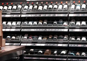 Weinregal mit vielen Flaschen in einem Weinladen, teils in Holzkisten.