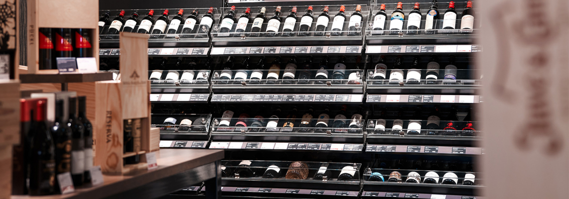 Weinregal mit vielen Flaschen in einem Weinladen, teils in Holzkisten.