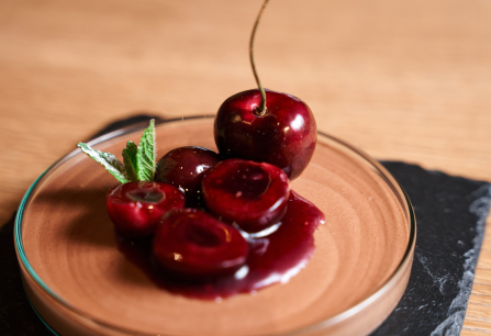 Kirschen mit Schokoladenmousse und Minze auf einem Glasteller.