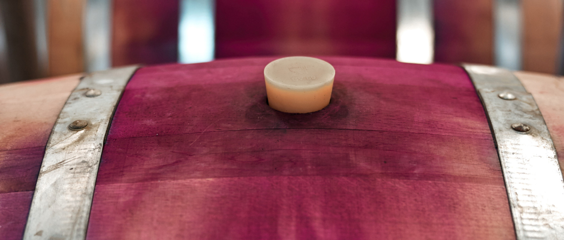 Nahaufnahme eines Holzfasses mit intensiv violetten Verfärbungen und Metallringen.