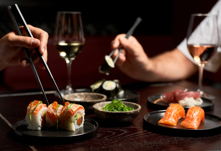 Zwei Personen genießen Sushi und Wein an einem elegant gedeckten Tisch.