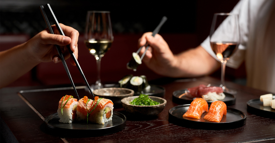 Zwei Personen genießen Sushi und Wein an einem elegant gedeckten Tisch.