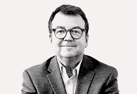 Schwarz-weiß Portrait eines Mannes mit Brille im Anzug, auf hellem Hintergrund.