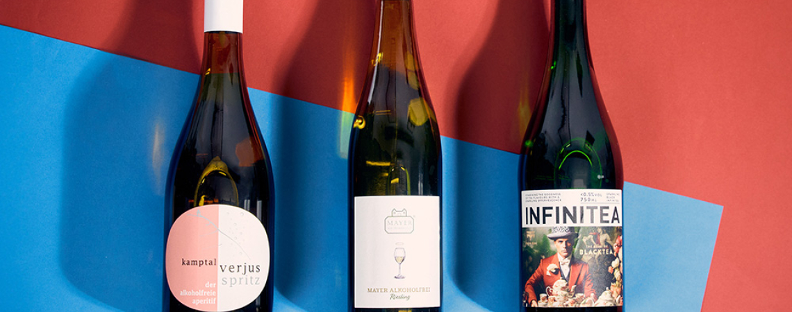 Drei Weinflaschen auf farbigem Hintergrund in Rot und Blau.