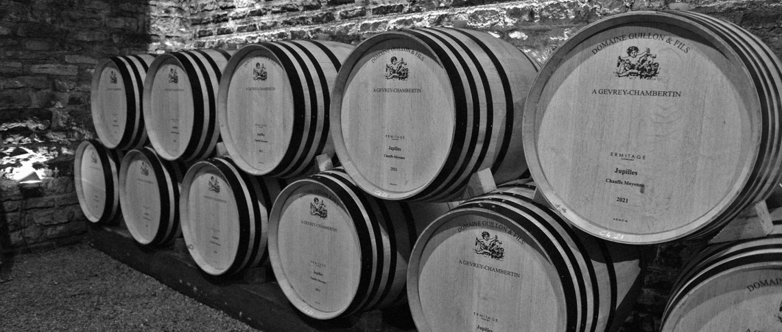 Holzfässer in einem Weinkeller auf rustikaler Steinwand.