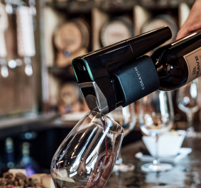 Wein wird mit einem schwarzen Gerät in ein Glas eingefüllt.