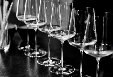 Reihe eleganter Weingläser auf dunklem Tisch, stilvoll präsentiert.