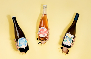 Drei Weinflaschen in Händen vor gelbem Hintergrund durchbrechen Papier.