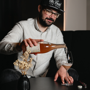 Mann mit Brille schenkt roséfarbenen Schaumwein in ein Glas ein.