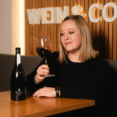 Person genießt Rotwein in stilvoller Umgebung mit Holzvertäfelung.