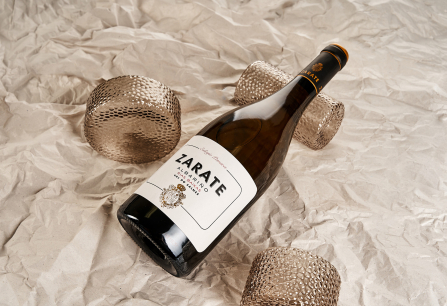 Weinflasche auf zerknittertem Papier mit dekorativen, texturierten Gläsern.