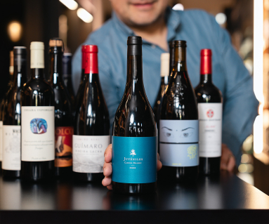 Mehrere Weinflaschen auf dunklem Tisch in Weinladen präsentiert.