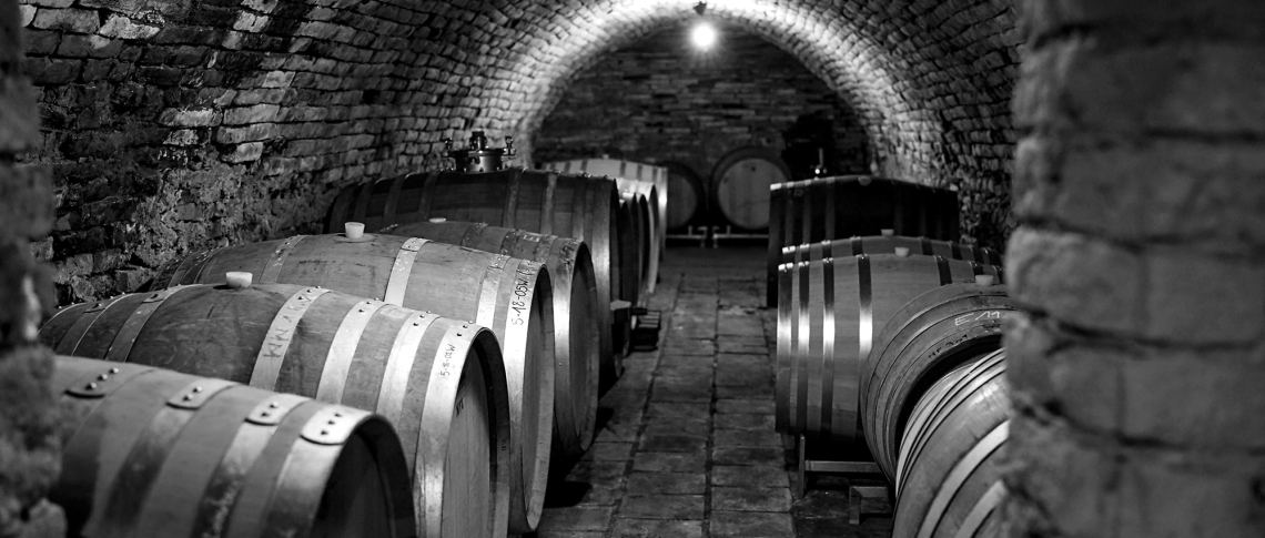 Gewölbekeller mit Holzfässern in Schwarz-Weiß.