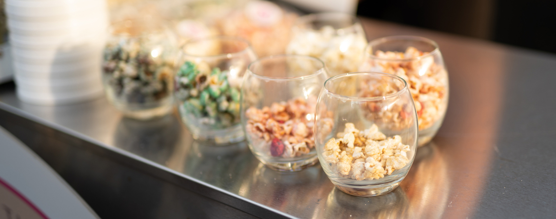 Transparente Gläser mit buntem Popcorn auf einer Metalloberfläche.