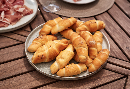 Goldbraune, knusprige Croissants auf einem runden Teller aus Steinzeug.