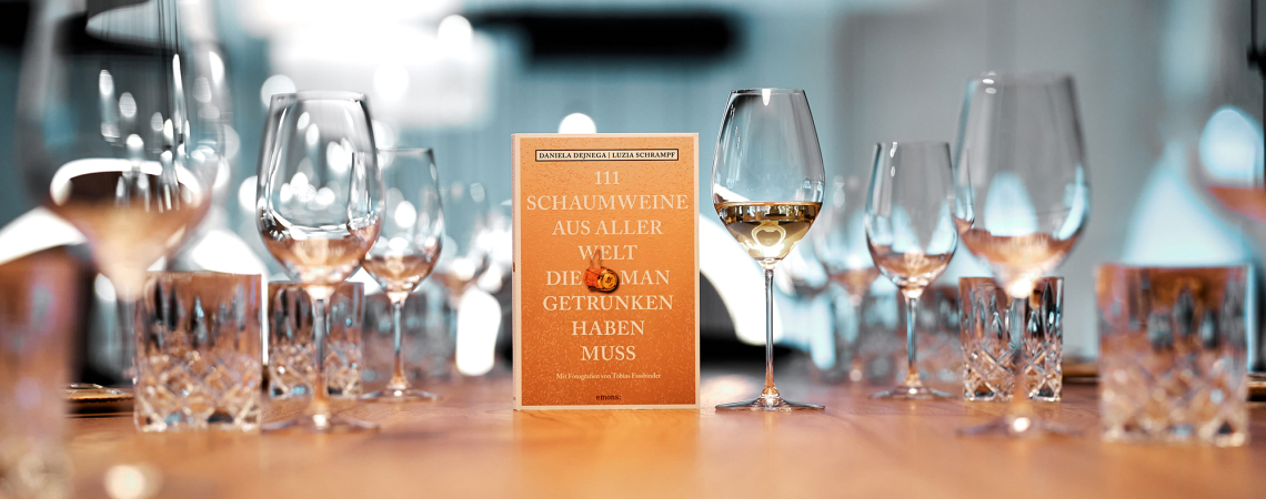 Buch auf Tisch umgeben von leeren Weingläsern und Kristallgläsern.