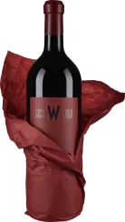 Eine Weinflasche mit dunkelrotem Etikett und Verschluss, eingewickelt in rotes Seidenpapier.