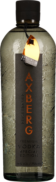 Transparente Flasche mit strukturierter Oberfläche und dunklem Verschluss; markante, vertikale Etikettierung in Orange und Schwarz; goldfarbenes Anhänger-Detail.