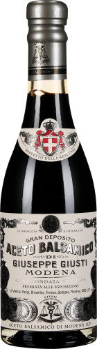 Dunkle Flasche mit reich verziertem weißen Etikett und silbernem Verschluss.