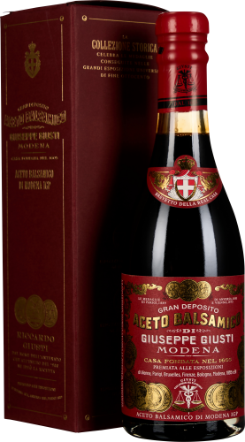 Eine elegante, dunkle Flasche Balsamico-Essig mit einem kunstvoll gestalteten roten Etikett und goldenen Verzierungen. Daneben steht eine passende, edle rote Verpackungsbox mit goldfarbenem Text.