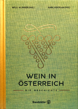 Buchcover in grünem Leinen, goldfarbene Verzierungen in Traubenform, schwarze und rote Schrift. Links gelber Buchrücken.