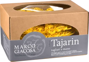 Braune Kartonverpackung mit ovalem Fenster, das goldgelbe, handgemachte Tagliatelle-Nudeln zeigt. Dezente graue Banderole mit kontrastierendem Text.