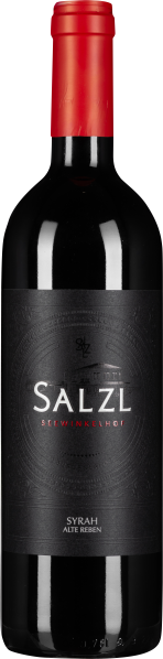 Die Weinflasche zeigt sich mit einem tiefschwarzen Etikett, verziert mit dezenten Prägungen und einem zentral platzierten, weiß-roten Schriftzug. Der Flaschenhals ist mit leuchtend rotem Folienverschluss abgedeckt.