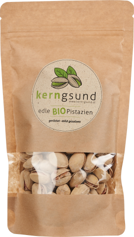 Nachhaltige braune Verpackung mit Sichtfenster, gefüllt mit Pistazien in der Schale. Runde Etikette mit grünen Details.