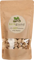 Nachhaltige braune Verpackung mit Sichtfenster, gefüllt mit Pistazien in der Schale. Runde Etikette mit grünen Details.