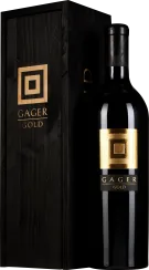 Schwarze Weinflasche mit goldener Etikettverzierung neben dunkler Holzkiste.