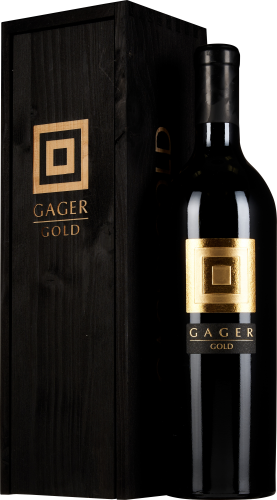 Schwarze Weinflasche mit goldener Etikettverzierung neben dunkler Holzkiste.