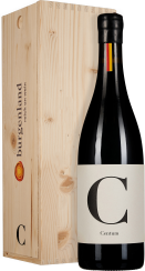 Dunkle Weinflasche mit schlichtem, elegantem Etikett, das einen großen Buchstaben zeigt. Neben der Flasche steht eine helle Holzkiste mit natürlicher Maserung.