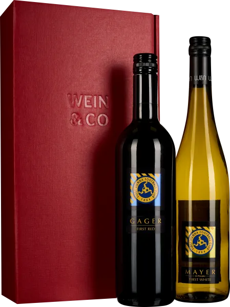 Rote Geschenkbox mit geprägtem Logo, enthält zwei Weinflaschen: Eine Rotweinflasche mit schwarzem Etikett und eine Weißweinflasche mit transparentem, goldgelbem Glas.