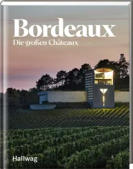 Buchcover mit Weingutgebäude in abendlicher Landschaft, umgeben von Weinreben.