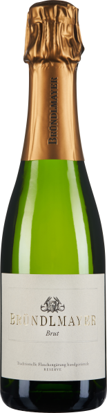 Die Flasche zeigt einen eleganten Sekt mit grüner Glasflasche und goldener Kapsel. Das Etikett ist schlicht und hell gehalten, mit einem stilisierten Logo in Schwarz und goldener Schrift.