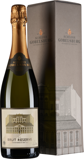 Flasche mit grünlichen, transparentem Glas und goldener Schaumweinkapsel, Etikett zeigt ein Schloss. Daneben eine schlichte, elegante Verpackung in Grau mit dezenten grafischen Linien des Gebäudes.