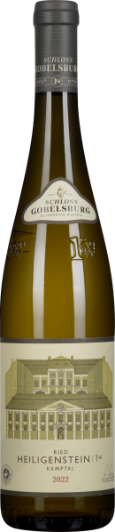 Eine schmale Weinflasche mit einem goldgelben Inhalt. Das Etikett zeigt eine detaillierte Abbildung eines herrschaftlichen Gebäudes in sanften Erdtönen, kombiniert mit eleganten Schriftzügen. Der Hals der Flasche ist mit einem dunklen, schlichten Kapselve