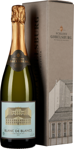 Flasche mit olivgrünem Glas und goldener Halsverpackung, daneben eine elegante, graue Geschenkbox mit schlichter Architekturzeichnung und dezenter Prägung.