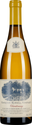 Flasche eines Weißweins mit gelber Flüssigkeit, kleinem Wappen oben und detaillierter Illustration einer Landschaft auf dem Etikett, das in Blau und Weiß gehalten ist.