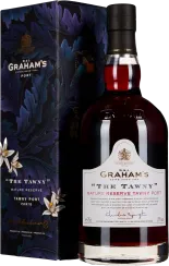 Eine dunkelrote Weinflasche mit elegantem Etikett und schwarzem Verschluss steht vor einer dekorativen Box mit blauen Blättern und weißen Blumen.