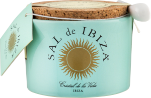 Helles, türkisfarbenes Keramikgefäß mit einem goldenen Sonnenemblem und Korkdeckel, begleitet von einem kleinen weißen Löffel. Ein Etikett ist an der Kordel befestigt.